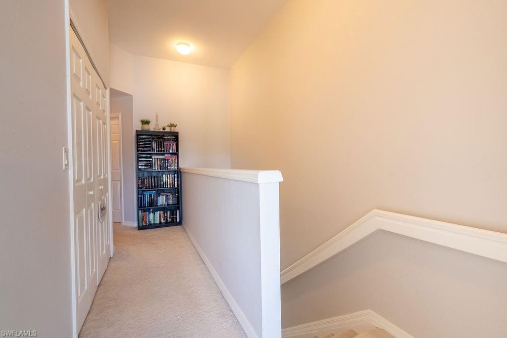 Hall featuring light colored carpet and an upstairs landing