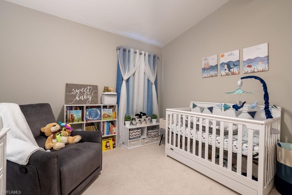 Bedroom with carpet floors, a crib, and vaulted ceiling