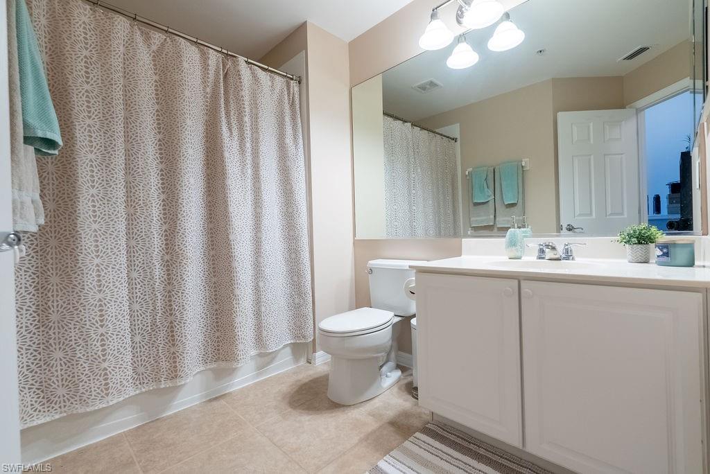 Full bathroom featuring vanity, light tile patterned flooring, a chandelier, and shower / bathtub combination with curtain