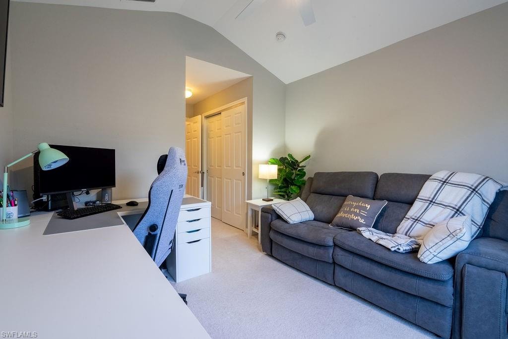 Office space featuring vaulted ceiling, light carpet, and a ceiling fan