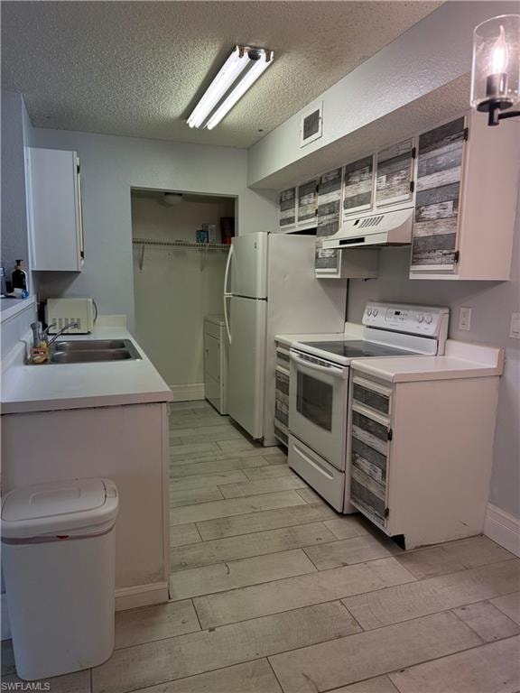 Kitchen featuring white appliances, upper and lower cabinetry with distressed wood-look accents, a stainless steel sink, and wood-finish flooring