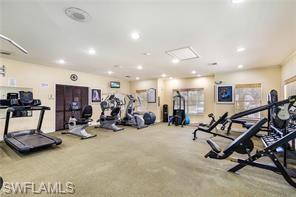 Fitness center featuring extensive cardio equipment, strength training stations, recessed lighting, wall-mounted mirrors, and exterior-facing windows