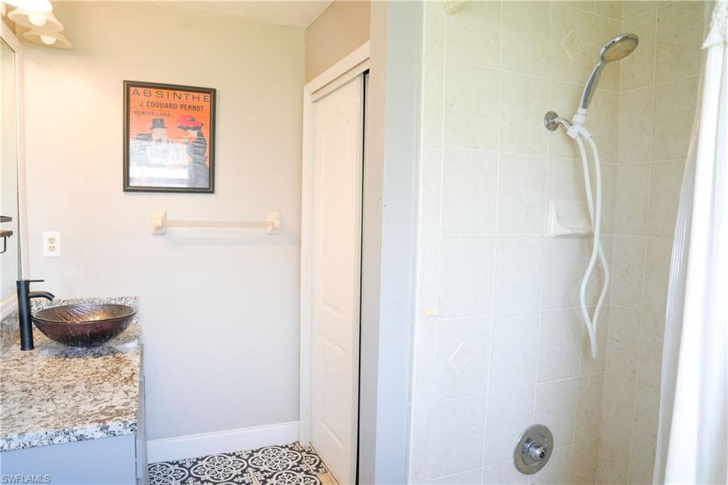 Bathroom vanity featuring a vessel sink with a dark bronze faucet, granite-style countertop, and patterned floor tile