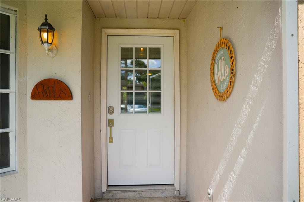 White paneled entry door with multi-pane glass insert and brass hardware