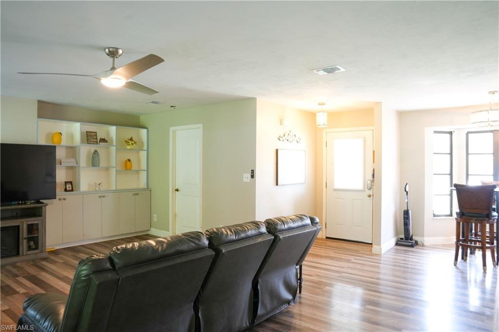 Living area featuring wood-finish flooring, a contemporary ceiling fan, and built-in cabinetry with open shelving