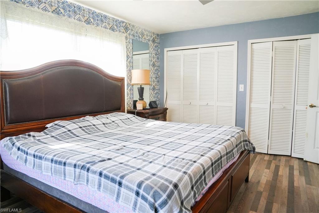 Spacious room featuring wood-finish flooring, light blue wall paint, and decorative wallpaper