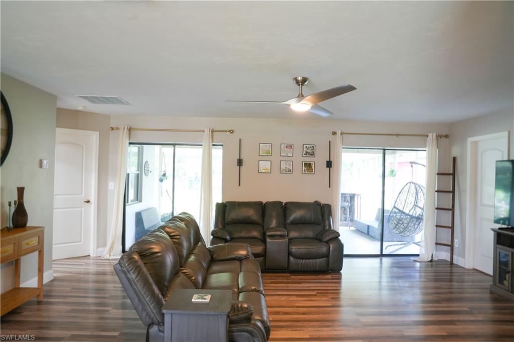 Spacious living area featuring wood-finish flooring, a contemporary ceiling fan, and large sliding glass doors leading to an outdoor space