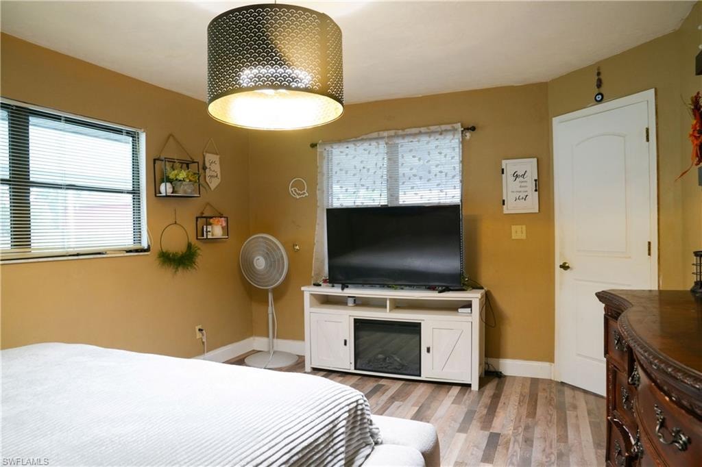 Warm-toned room featuring a decorative drum pendant light and wood-finish flooring