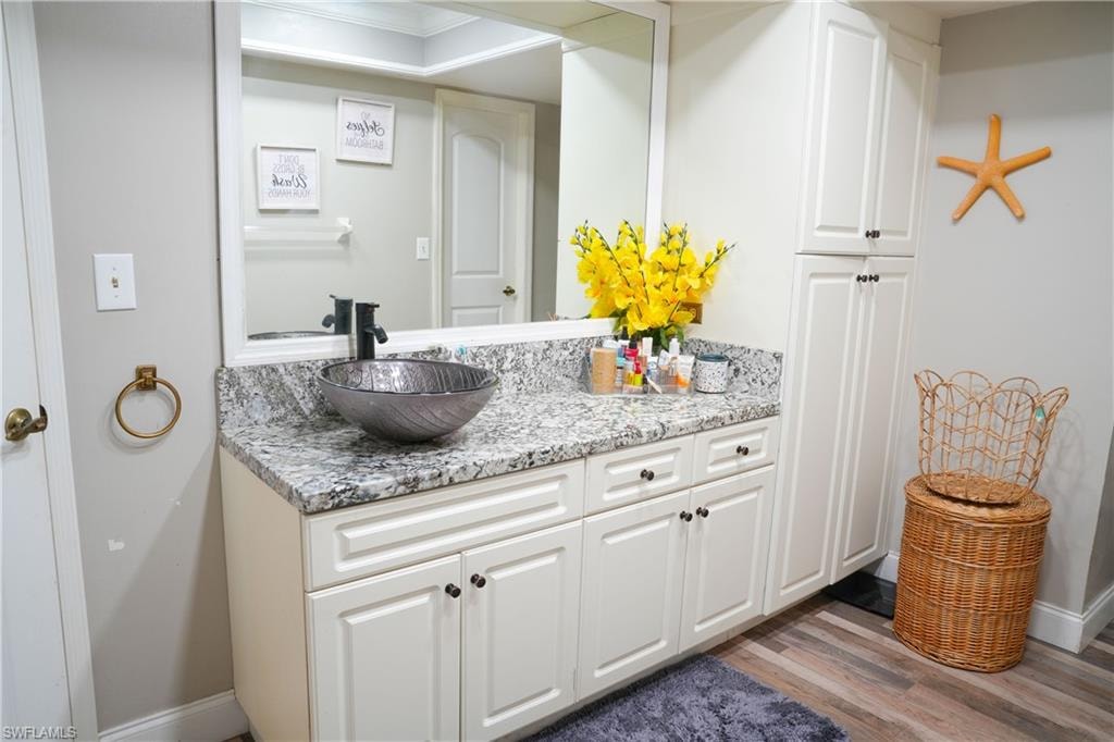 Bathroom vanity featuring a vessel sink with a dark finish, granite-style countertop, and white cabinetry