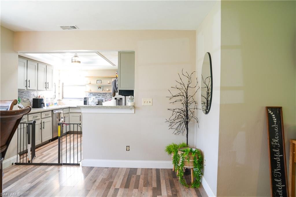 Kitchen pass-through with granite-style countertop, featuring light gray cabinetry and a mosaic tile backsplash