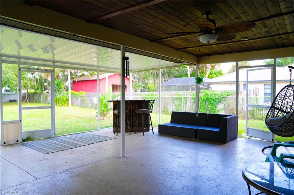Screened-in patio with concrete flooring and a wood-finish ceiling featuring a ceiling fan
