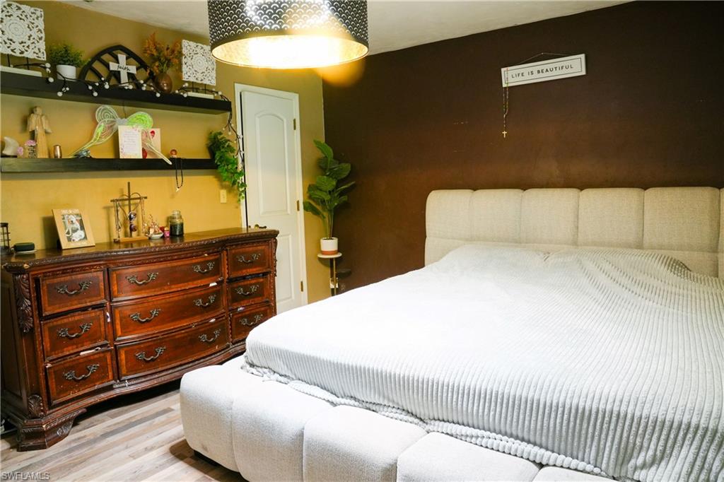 Bedroom featuring a neutral upholstered bed frame, two-toned wall finishes, and wood-finish flooring
