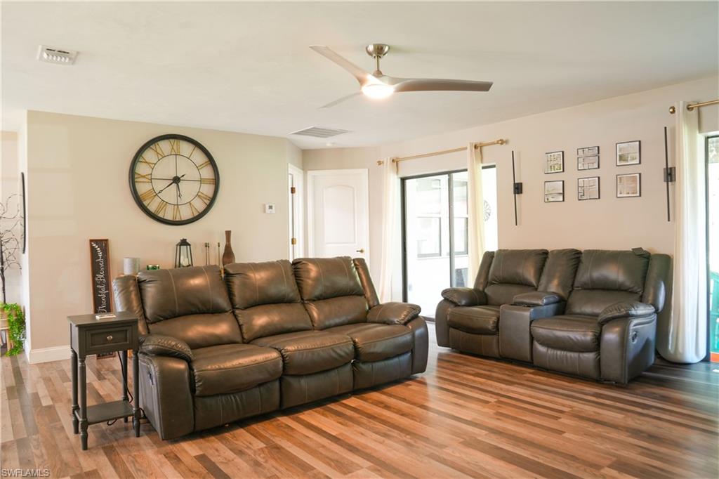 Living area featuring wood-finish flooring, a ceiling fan with integrated lighting, and neutral wall tones