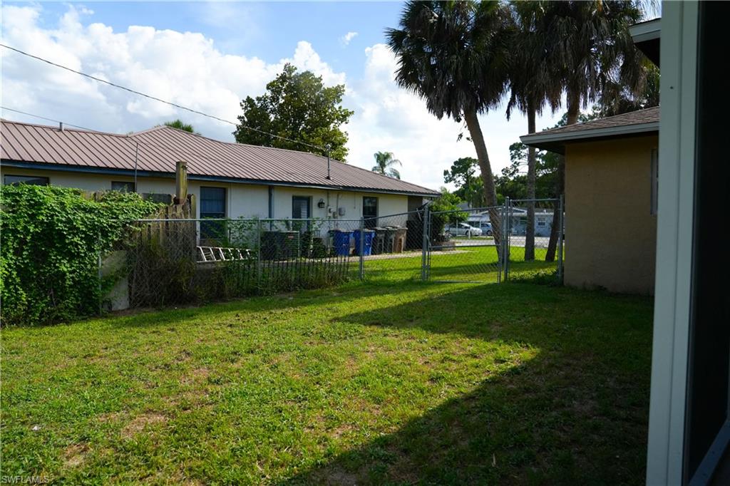 Grassed yard area featuring chain link fencing and mature palm trees