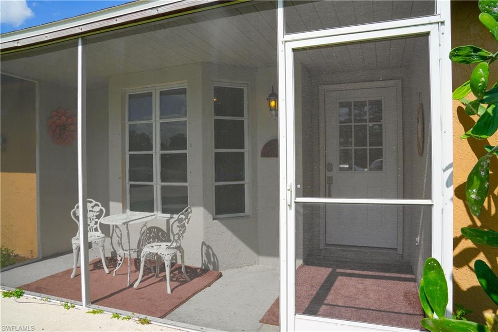 Screened entry porch featuring a white paneled door with window inserts