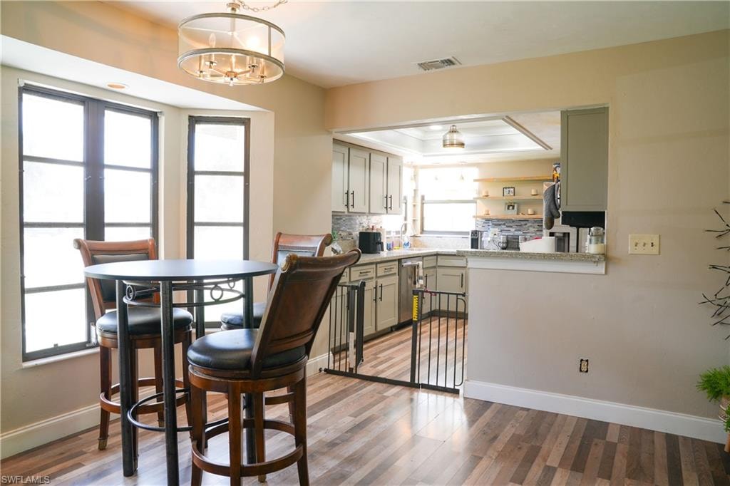 Dining area featuring wood-finish flooring, a contemporary drum chandelier, and a bay window with dark-framed panes