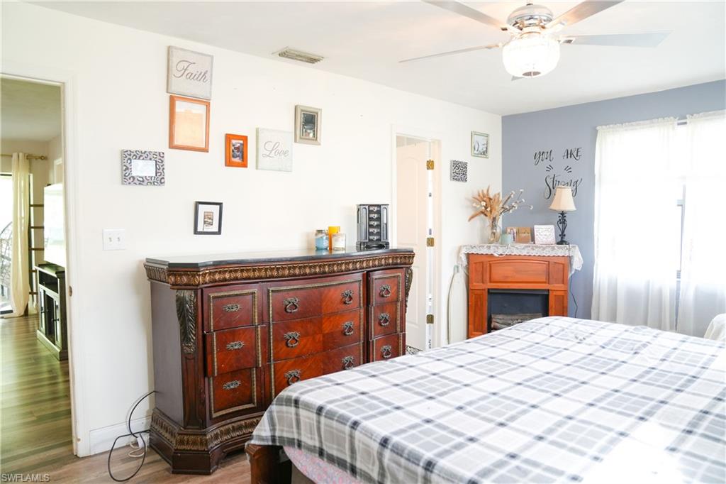 Spacious room featuring wood-finish flooring, a ceiling fan with integrated lighting, and a window with white sheer curtains