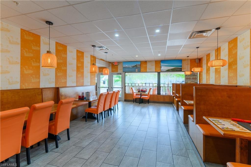 Spacious interior featuring a combination of booth and table seating, light-toned tile flooring, drop ceiling with recessed lighting, and large windows