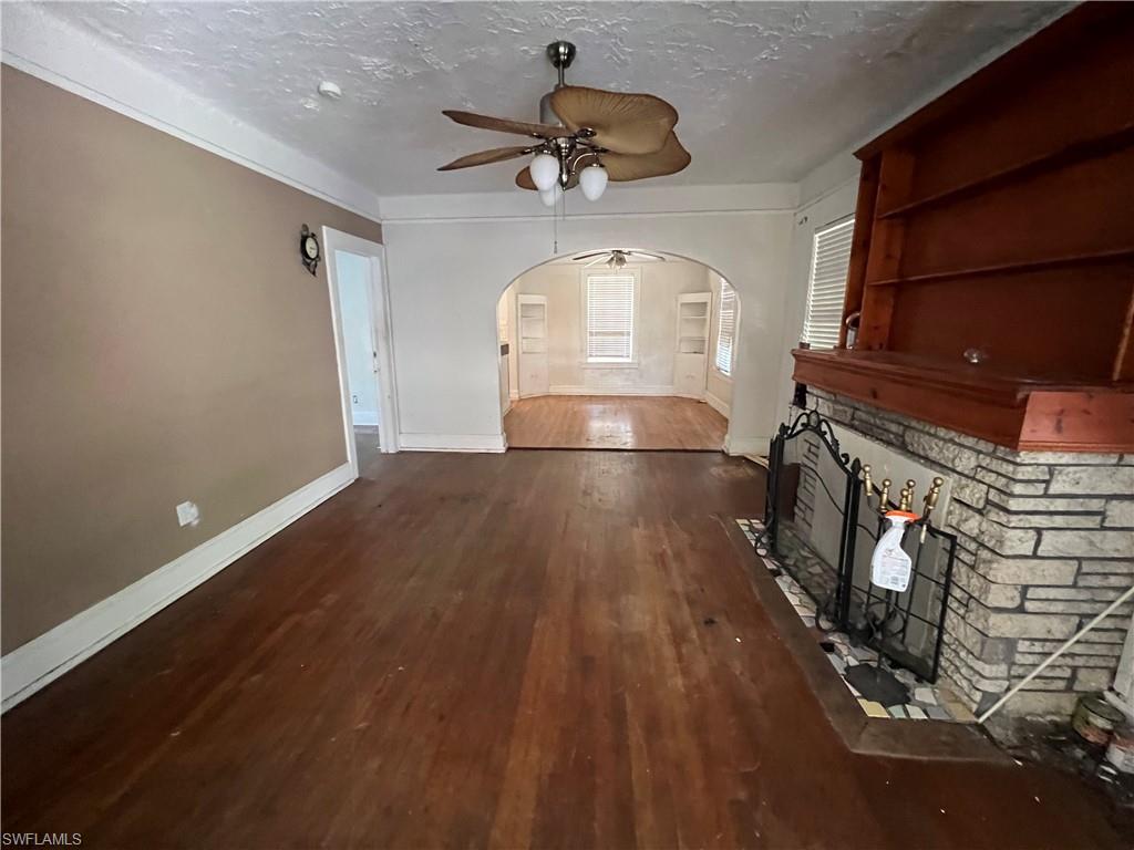 Living area featuring rich wood-finish flooring and a stone-clad fireplace with a wood mantel