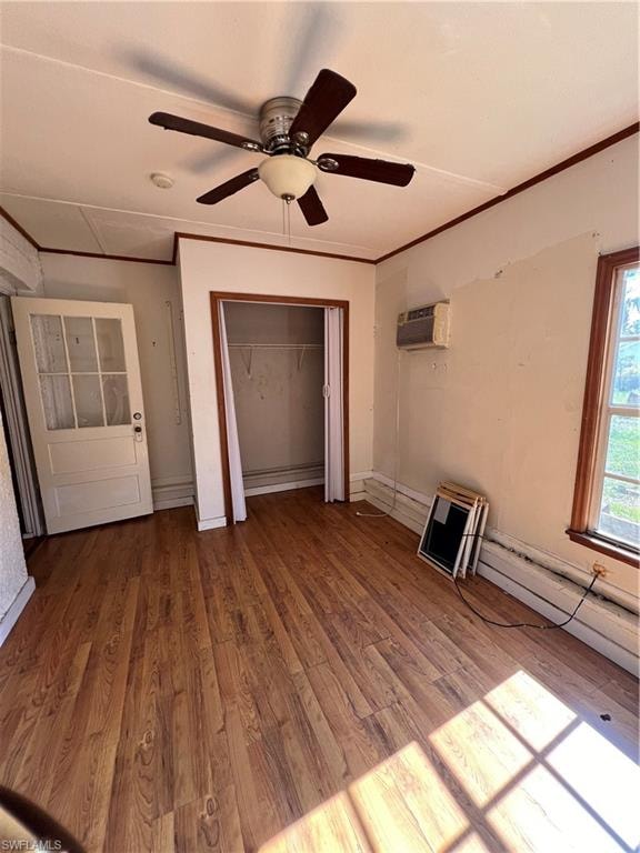 Room featuring wood-finish flooring, a ceiling fan with light fixture, and an open closet space