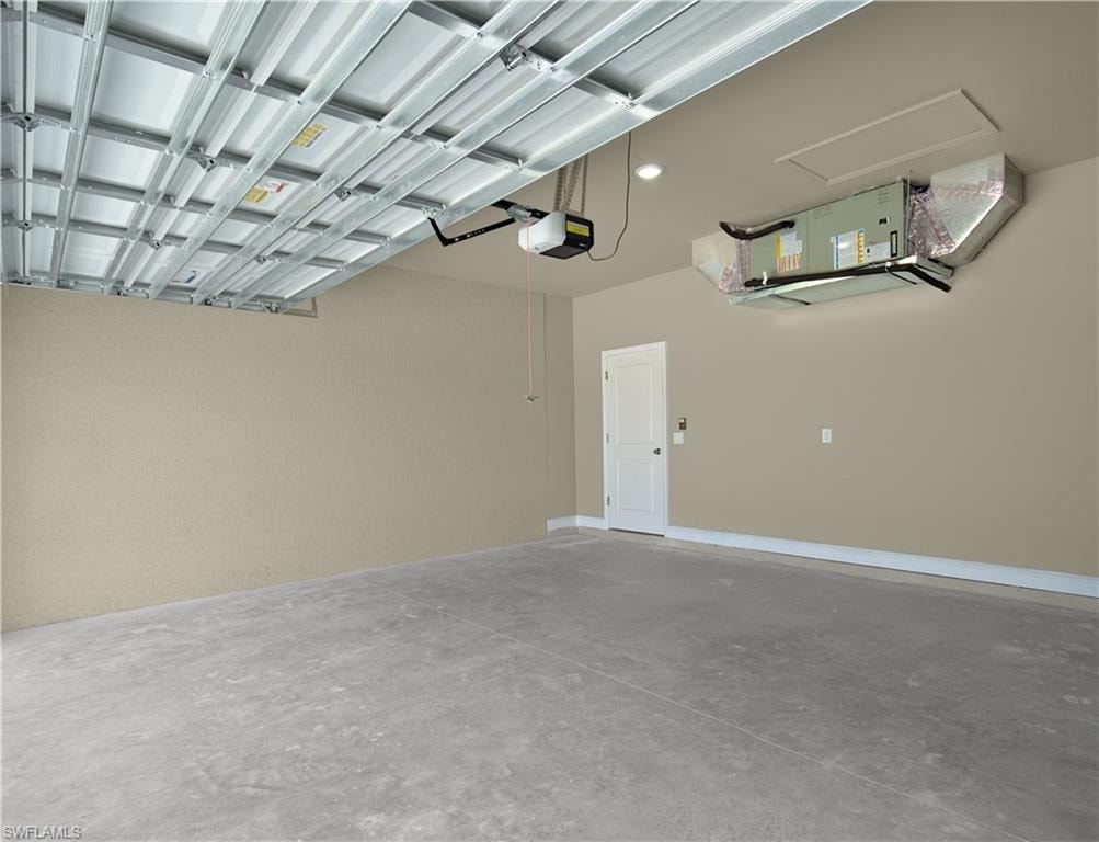 Spacious garage featuring a concrete floor, light beige painted walls, and a white interior door with dark hardware
