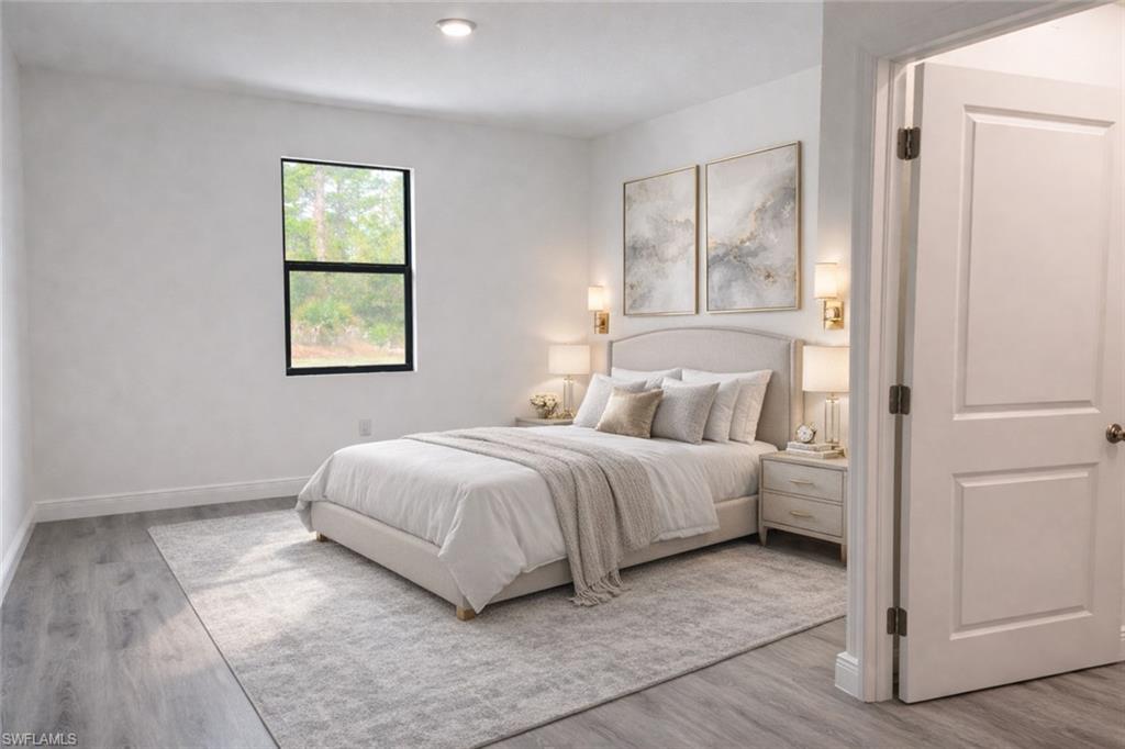Light-filled sleeping area featuring wood-finish flooring, a contemporary window, recessed lighting, a paneled interior door, and a neutral color palette