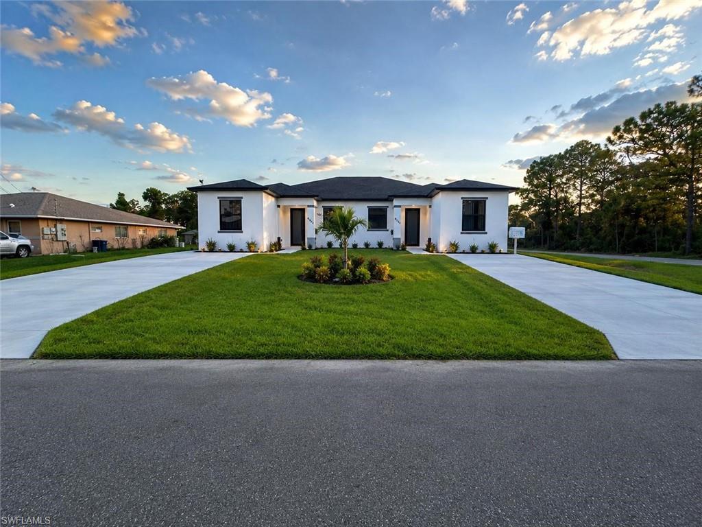 Modern white stucco facade featuring dark-framed windows and a dark roof