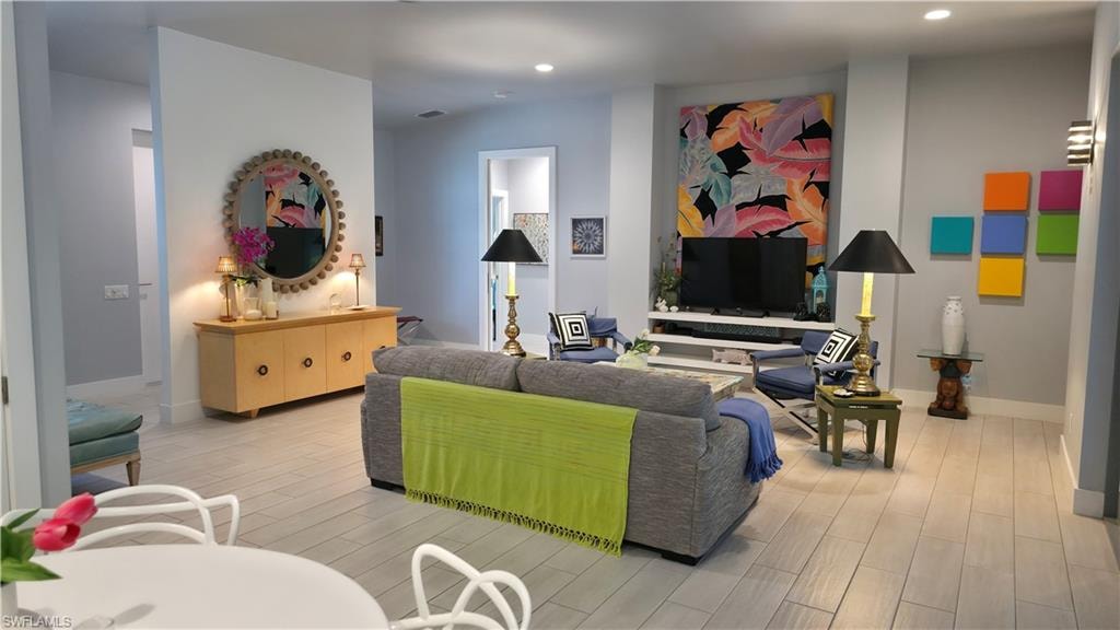 Spacious living area featuring light wood-finish flooring, a built-in media console, recessed lighting, and wall sconces