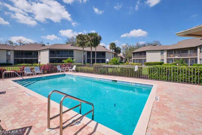 Community pool featuring a patio, fence, and a residential view