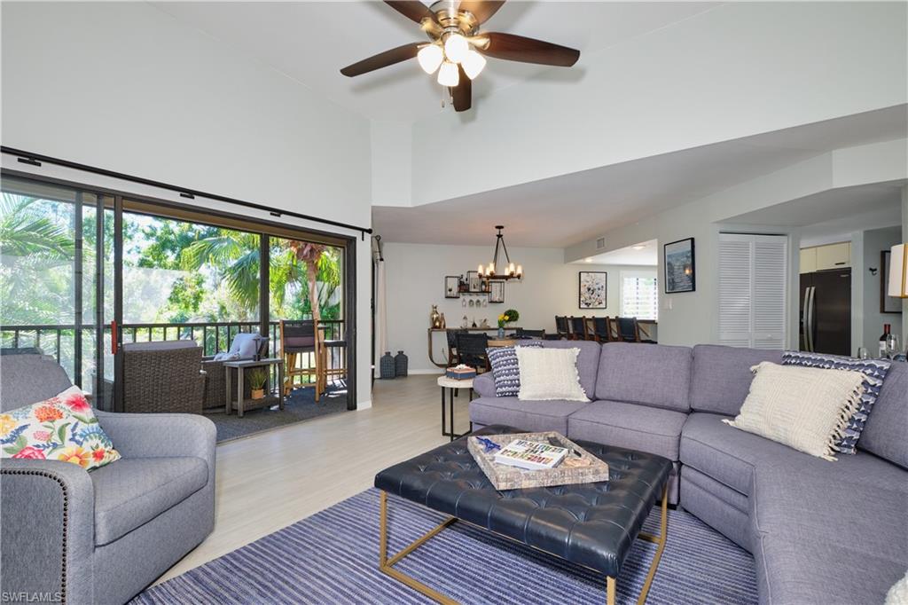 Living area featuring ceiling fan with notable chandelier, a towering ceiling, and wood finished look LTV floors