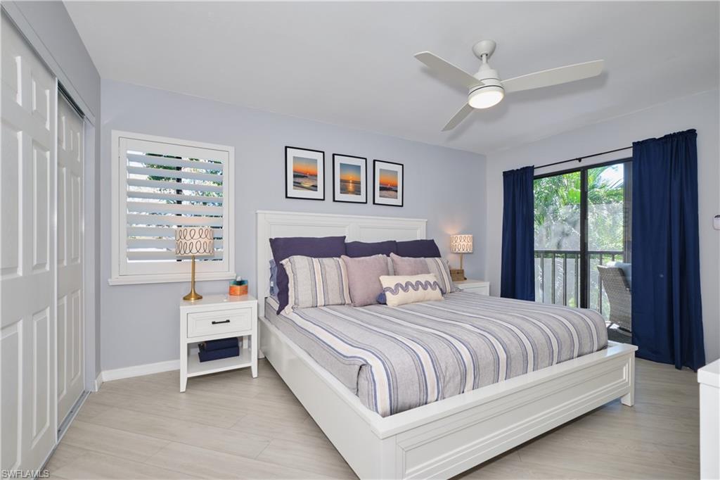 Bedroom featuring lighted ceiling fan, sliders give access to outside, two closets, and light wood-like LTV floors.