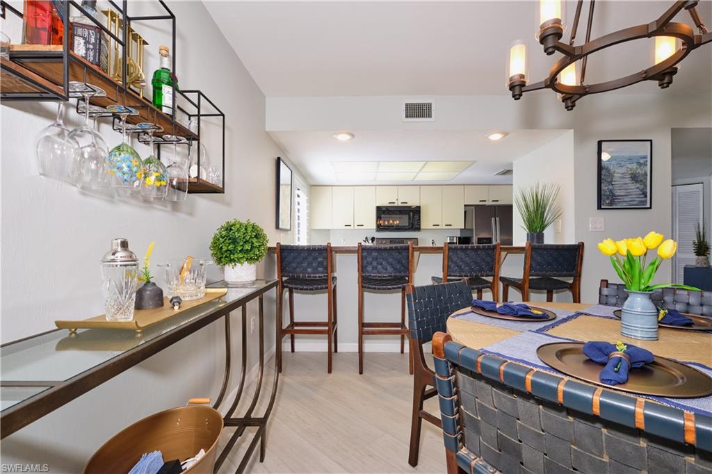 Dining space offers plenty room for entertaining with breakfast bar, living/dinging combo, light wood-style LTV floors, recessed lighting, a chandelier.