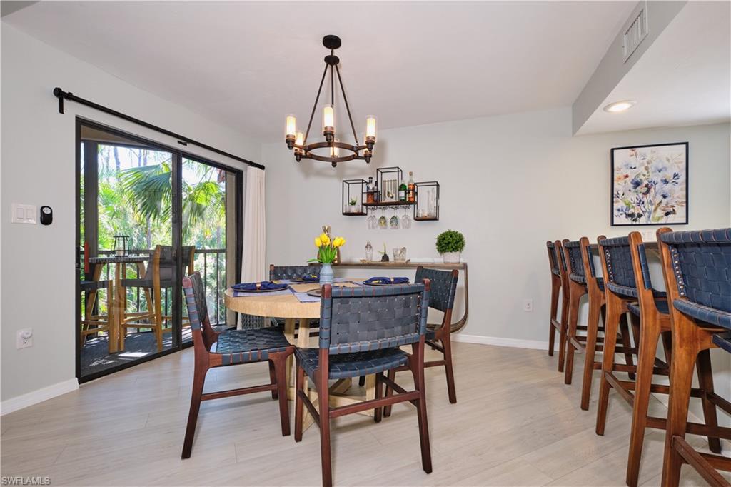 Dining area with a stylish chandelier, recessed lighting, light wood-style LTV floors.
