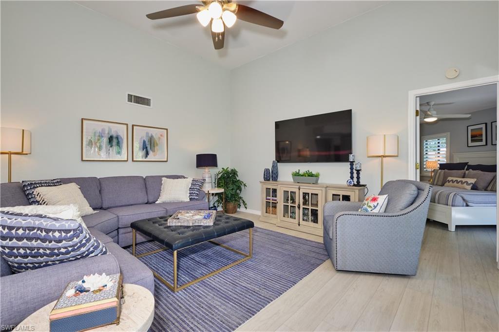 Living room featuring high vaulted ceiling, lighted ceiling fan, and wood-style LTV finished floors
