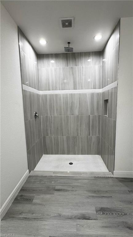 Walk-in shower featuring vertically laid gray-toned wall tiles with decorative horizontal stripe accents