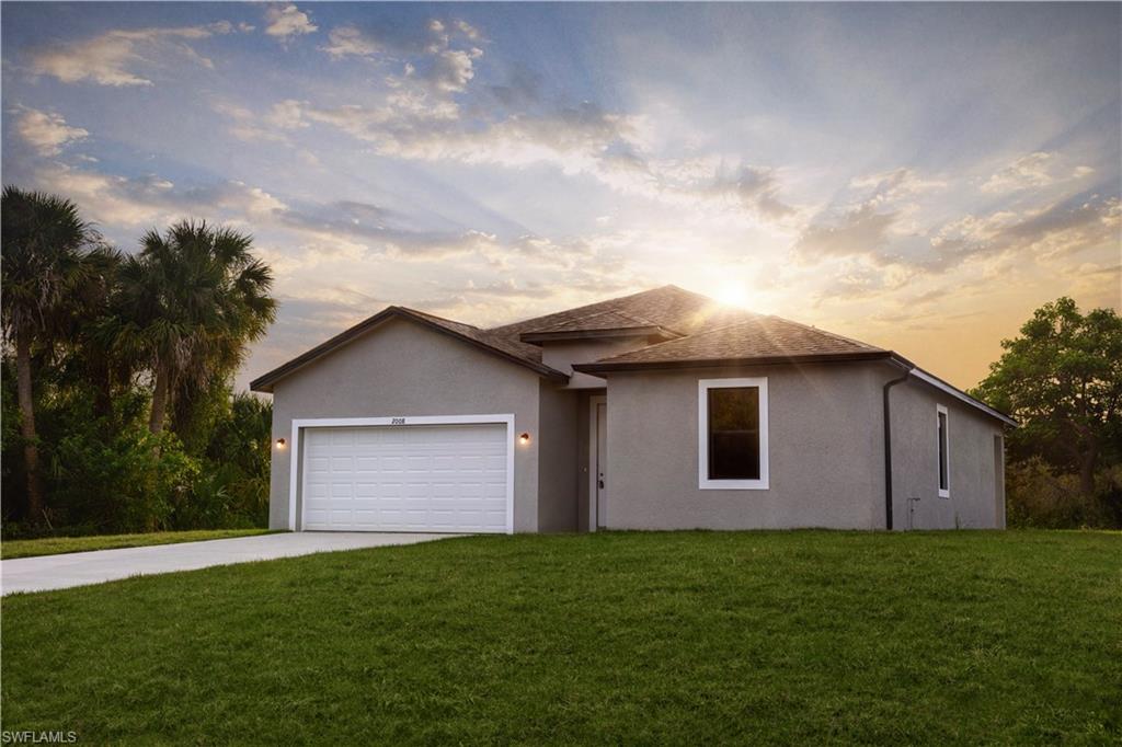 Contemporary stucco exterior with a prominent two-car garage, manicured lawn, paved driveway, and multiple windows with white trim