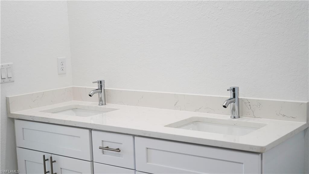 Dual vanity with white shaker-style cabinetry, chrome hardware, and undermount sinks set in a light-toned countertop with integrated backsplash