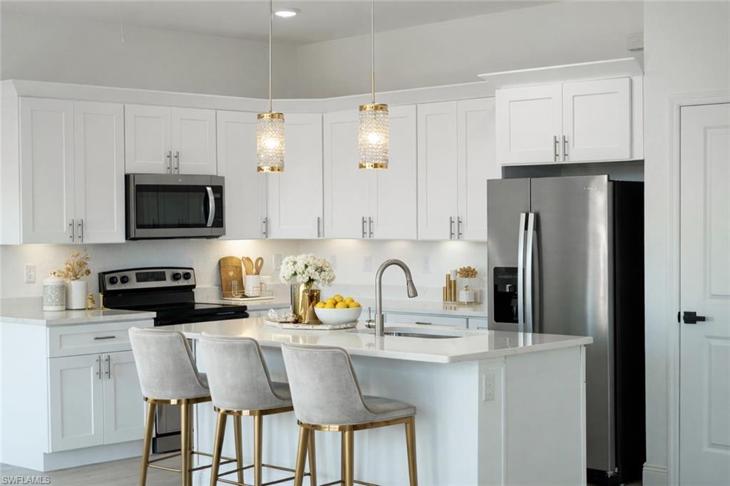 Contemporary kitchen featuring white shaker cabinetry, stainless steel appliances, a center island with sink, and pendant lighting
