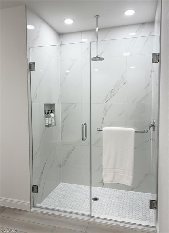 Glass-enclosed shower with large format tile walls and a hexagonal tile floor