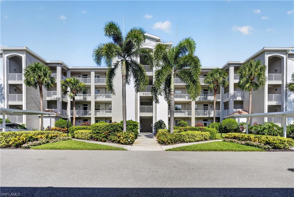 Multi-story residential building with light gray stucco exterior and white railings