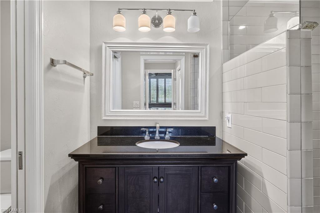 Vanity featuring a dark wood finish, a black countertop, and a white undermount sink