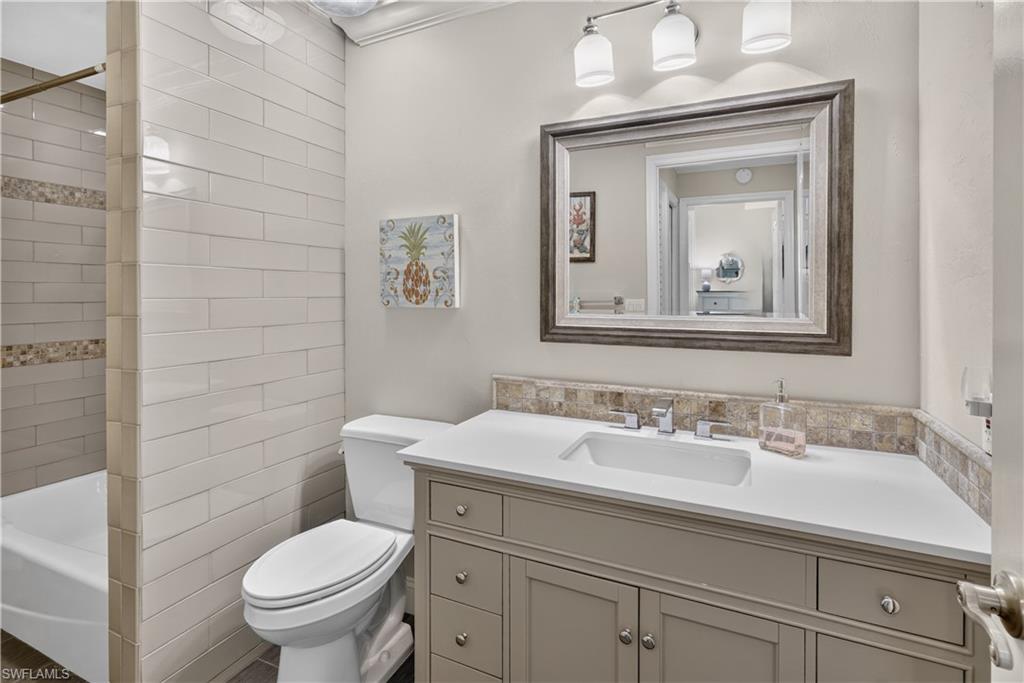 Bathroom featuring a vanity with a white countertop and undermount sink, framed mirror, and a three-light fixture