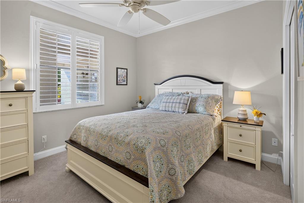 Room featuring light gray wall paint, white crown molding, a ceiling fan with integrated lighting, wood-finish flooring, and a window with white plantation shutters