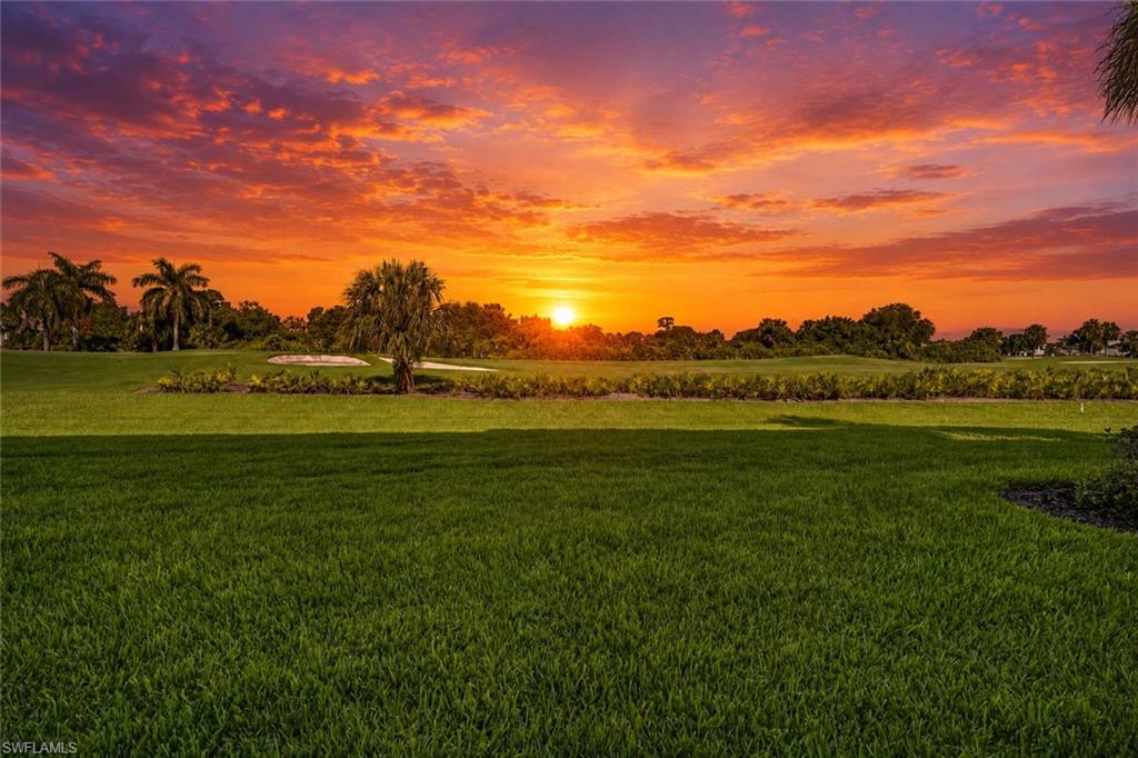 Expansive green lawn extending to a golf course with sand traps and palm trees