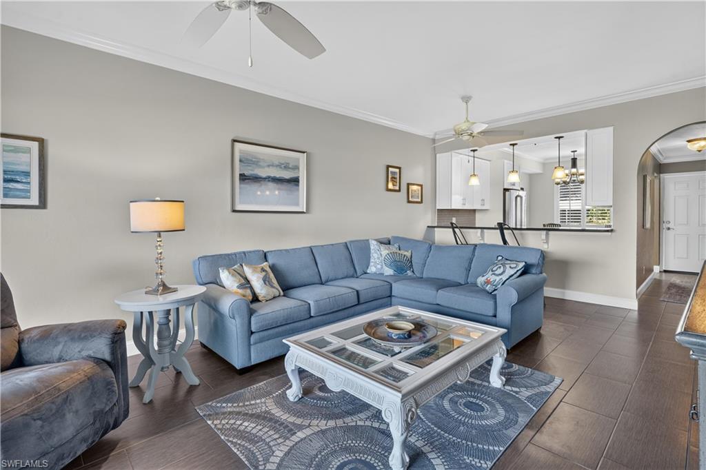Spacious living area featuring dark wood-finish flooring, crown molding, and a ceiling fan