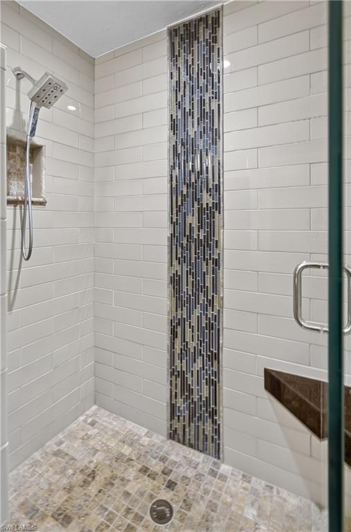 Tiled shower with a vertical mosaic accent stripe, subway tile walls, and a built-in corner bench