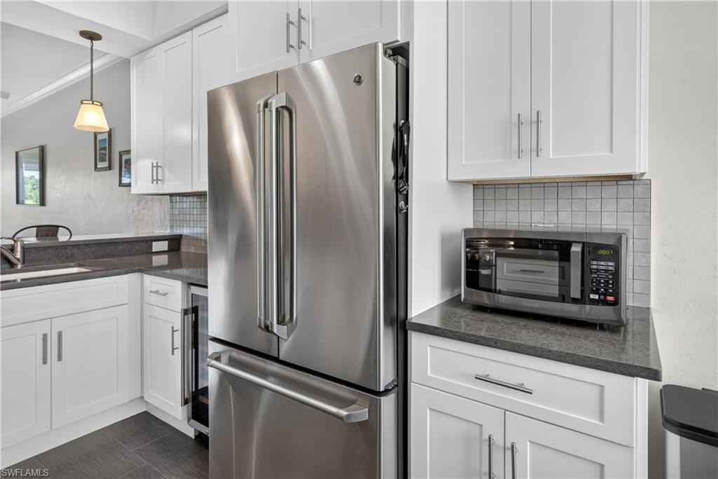 Kitchen featuring white shaker cabinetry, stainless steel French door refrigerator, dark stone countertops, and a subway tile backsplash