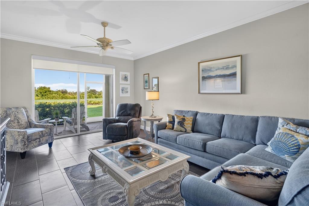 Living area featuring large format tile flooring, crown molding, and a ceiling fan