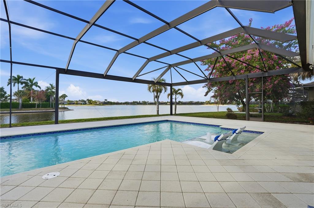 Screened pool enclosure featuring a rectangular swimming pool with integrated spa, bordered by light-toned paver decking