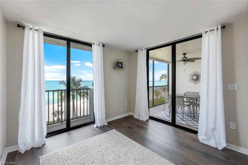 Empty room with a water view, dark hardwood / wood-style flooring, and expansive windows